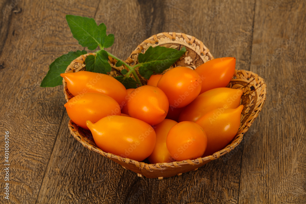 Yellow tomato heap in the wooden bowl Yellow tomato heap in the wooden bowl