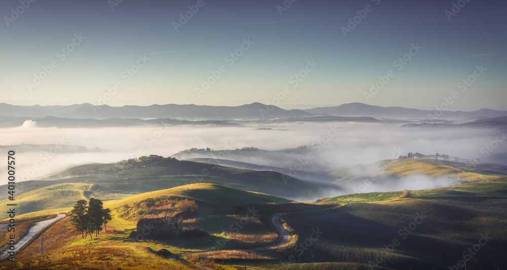 Volterra foggy landscape, rolling hills and green fields at sunrise. Tuscany, Italy