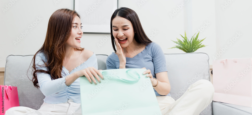 Two Asian beauty people opening the paper bag With a happy smiling face, being a new normal online business In the shopping experience from home Two Asian beauty people opening the paper bag With a happy smiling face, being a new normal online business In the shopping experience from home