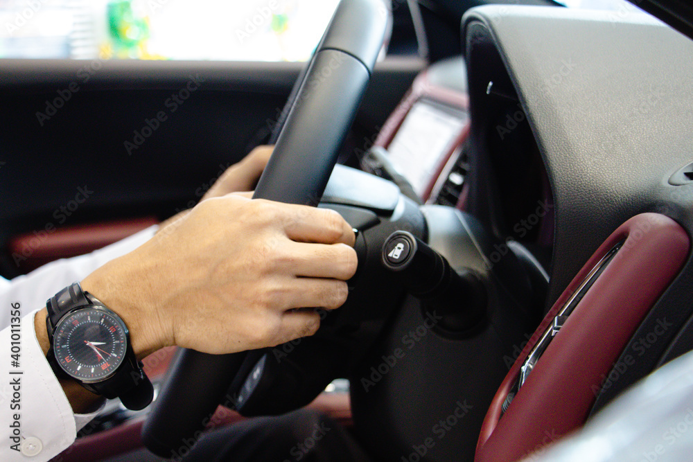 Close-up A businessman Hands put a watch Holding Steering Wheel with red console. Driving car concept.