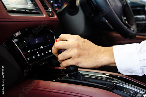 Hand of Business man driver shifting  the gear stick with red console. Driving car concept. Safe driving concept.