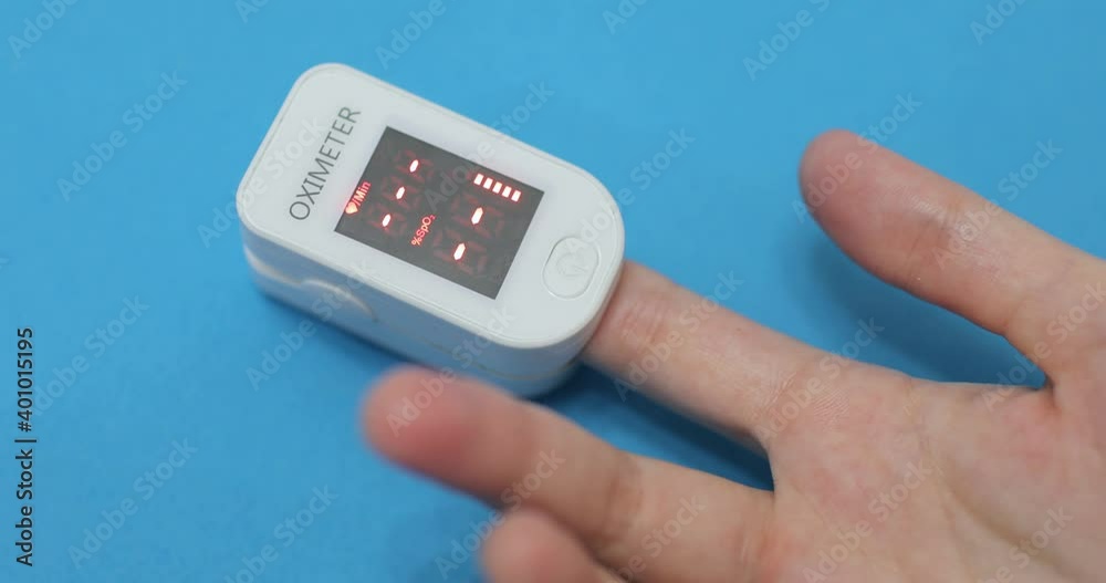 Modern technologies for health protection at home during coronavirus pandemic, covid-19 epidemic. Woman is measuring level of oxygen saturation of blood using pulse oximeter on blue background. Modern technologies for health protection at home during coronavirus pandemic, covid-19 epidemic. Woman is measuring level of oxygen saturation of blood using pulse oximeter on blue background.
