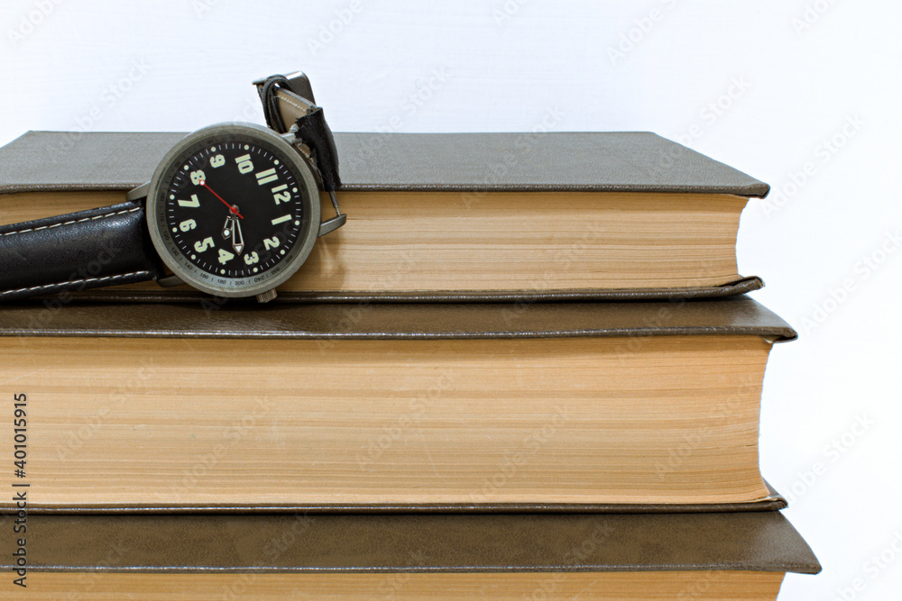 old watch on stack of old yellowed hardback books old watch on stack of old yellowed hardback books