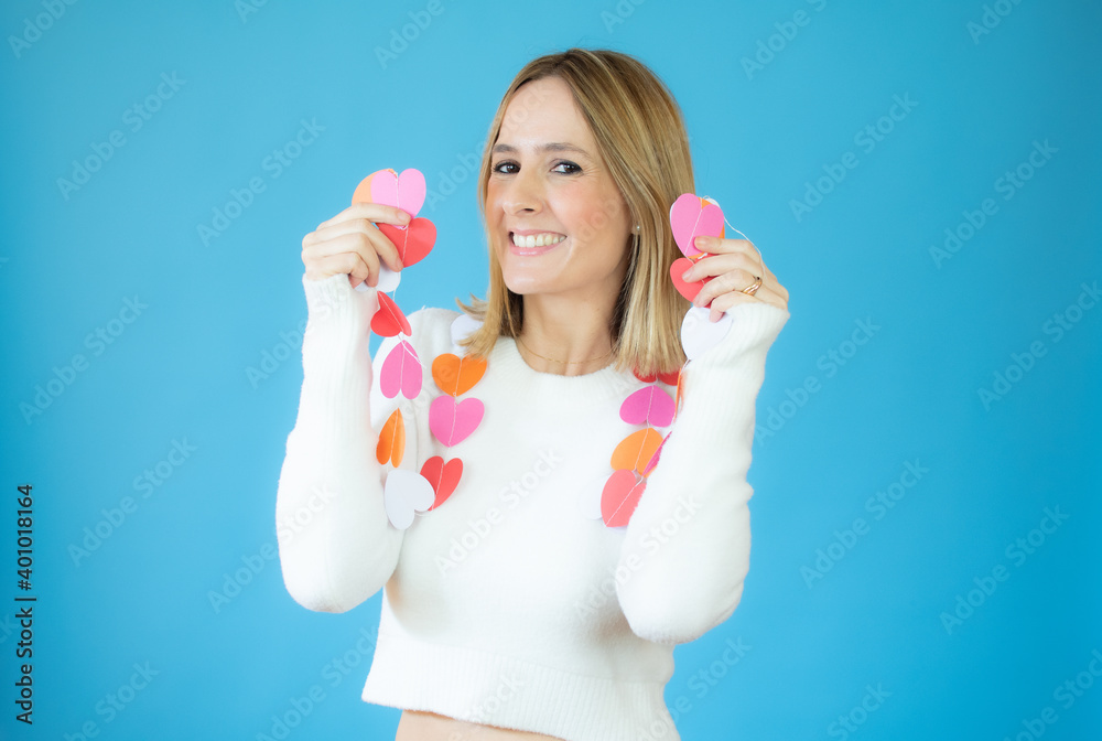 Happy young woman holding paper hearts over blue background. Happy young woman holding paper hearts over blue background.