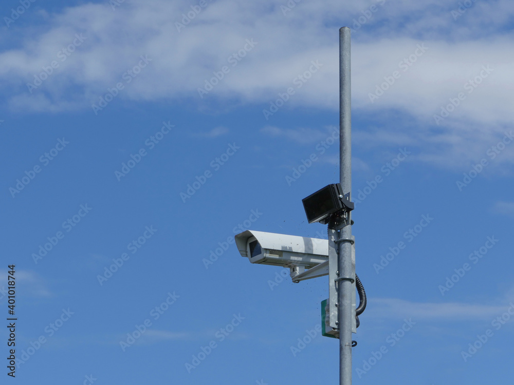 Surveillance camera on a pole high in the blue sky Surveillance camera on a pole high in the blue sky