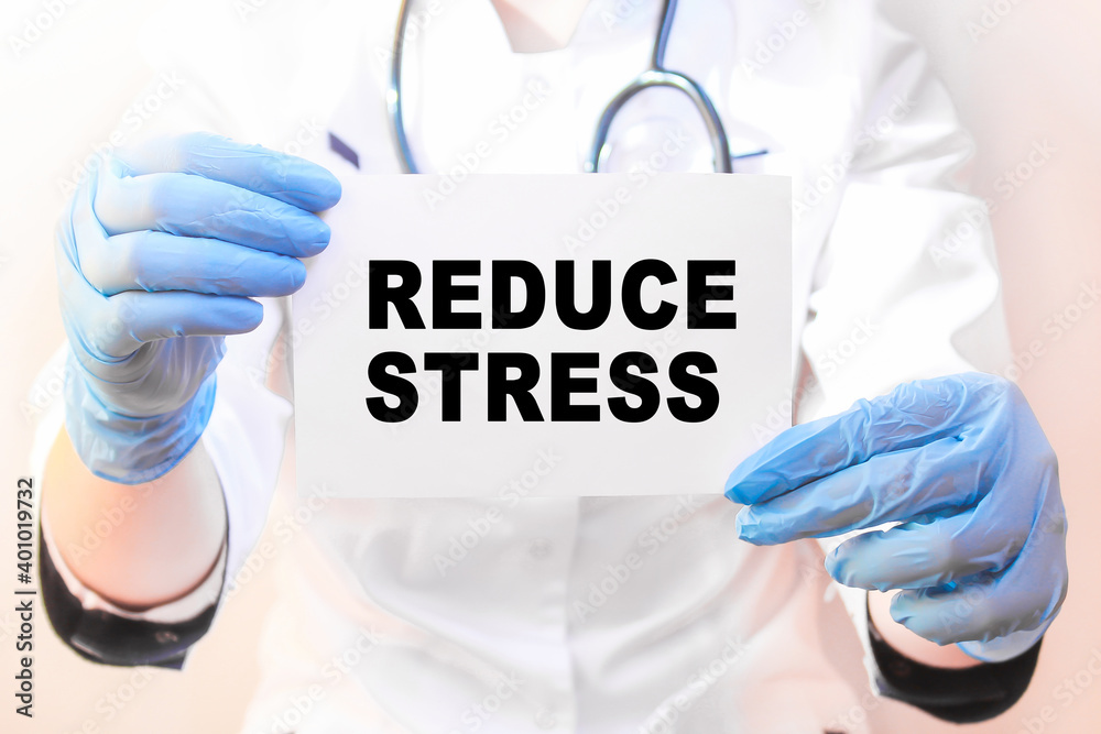 The doctor's blue - gloved hands show the word REDUCE STRESS - . a gloved hand on a white background. Medical concept. the medicine The doctor's blue - gloved hands show the word REDUCE STRESS - . a gloved hand on a white background. Medical concept. the medicine