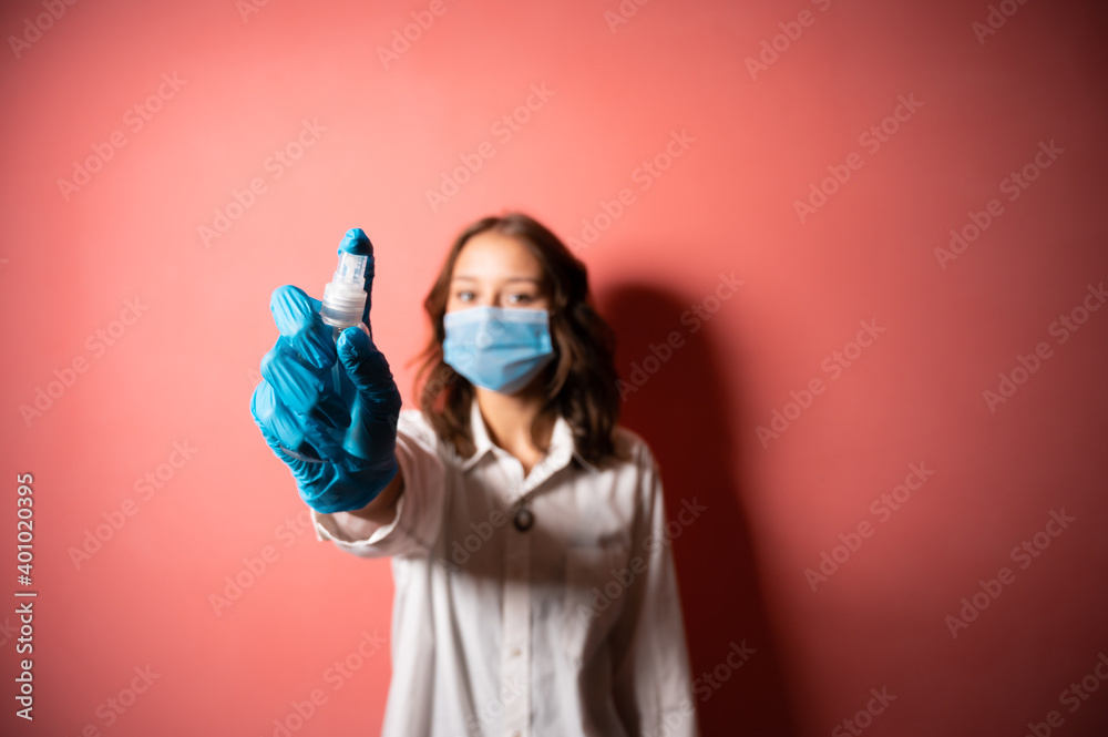 A girl of European appearance stands on a pink background and holds an antiseptic in her hands. Fighting Coronavirus. A girl of European appearance stands on a pink background and holds an antiseptic in her hands. Fighting Coronavirus.