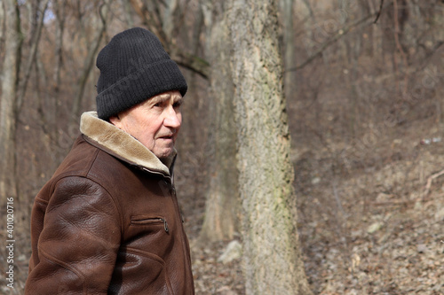 Portrait of elderly man standing in winter forest. Concept of old age, life in village