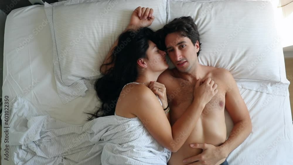 Young couple laid in bed waking up, top view Young couple laid in bed waking up, top view