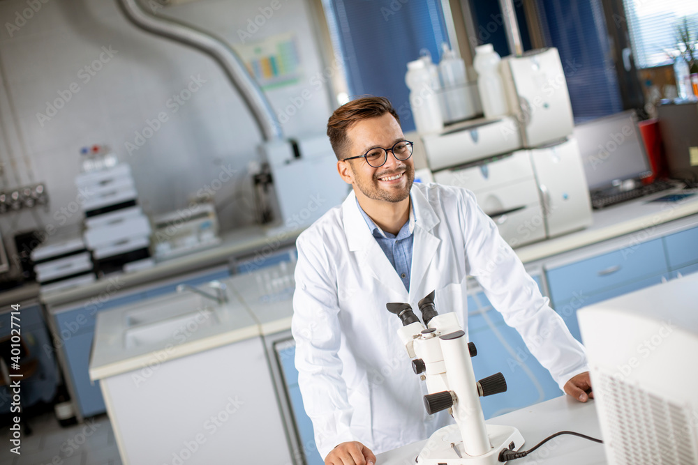 Young scientist in white lab coat working with binocular microscope in the material science lab Young scientist in white lab coat working with binocular microscope in the material science lab