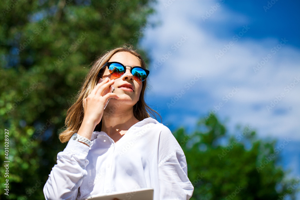 Young assistant in a white blouse phoning on the street Young assistant in a white blouse phoning on the street