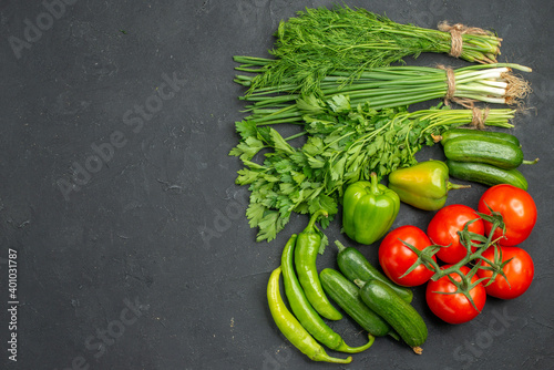 Overhead view of collection of fresh various organic vegetables and greens on dark background