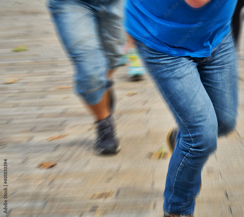 Concept to escape, run away, flee, run: Legs in blue denim pants running fast away from a pursuer, motion blur Concept to escape, run away, flee, run: Legs in blue denim pants running fast away from a pursuer, motion blur