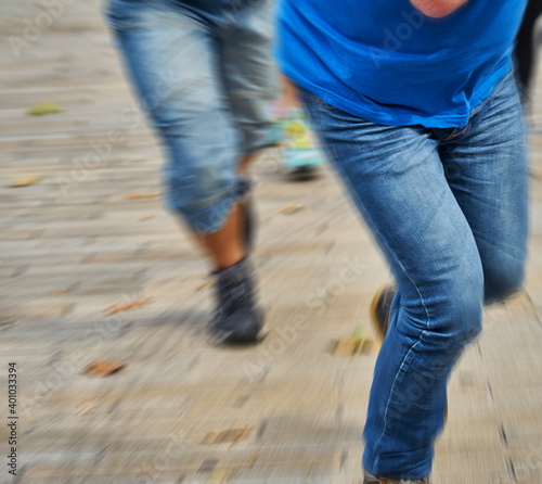 Concept to escape, run away, flee, run: Legs in blue denim pants running fast away from a pursuer, motion blur