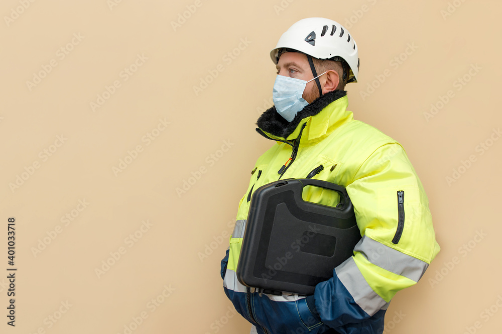 Male bearded industrial worker in hard hat with toolbox. Man engineer with white hard hat. Worker with medical mask.Climber