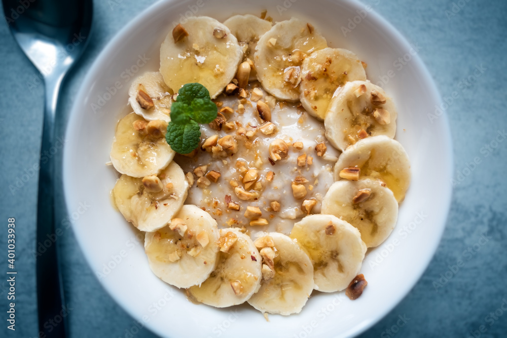 Oatmeal with banana, nuts and honey in white bowl closep. Natural health dieting food Oatmeal with banana, nuts and honey in white bowl closep. Natural health dieting food