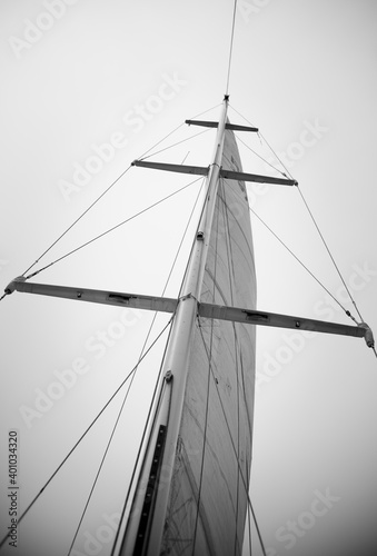 Sails of a sailing yacht in the wind sailing on the sea. Looking up at sail boat mast and rigging. In monochrome.