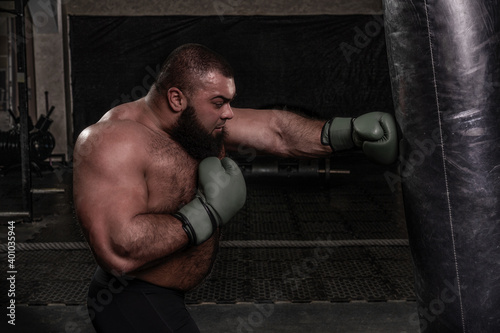 bearded heavyweight boxer practicing punching a punching bag