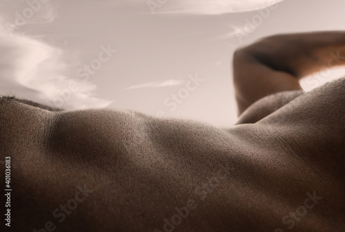 Valley. Detailed texture of human skin. Close up of young african-american male body surface like landscape with the sky on background. Skincare, bodycare, healthcare, inspiration, fantasy artwork.