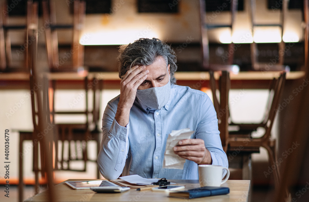 Frustrated owner sitting at table in closed cafe, small business lockdown due to coronavirus. Frustrated owner sitting at table in closed cafe, small business lockdown due to coronavirus.