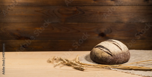 homemade bread and ears of wheat are on wooden rustic  background