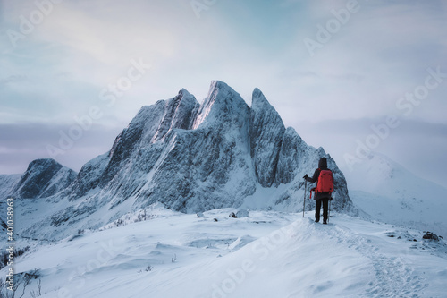 Mountaineer woman standing on top of Segla peak with majestic mountain in snowy on winter at Senja