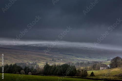 Snow covered fells of Cumbria as ominous looking clouds loom overhead