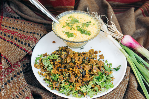 Close up shot of Indian food Kathiavadi dish - Vagarelo Rotlo made from pearl millet and spicy curd with onion and garlic on traditional background photo