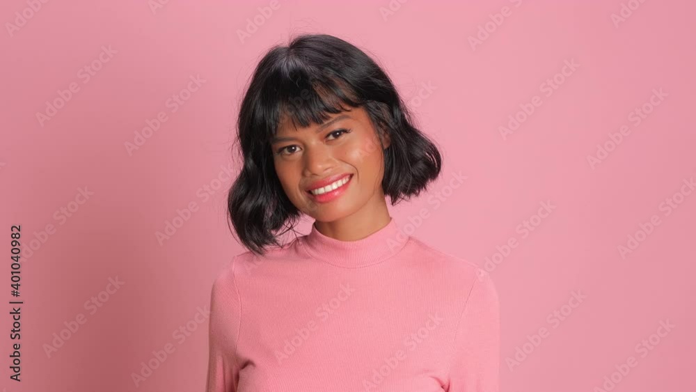 Overjoyed carefree woman grins happily smiles broadly shows white perfect teeth giggles over something very funny expresses positive emotions wears casual jumper isolated on pink studio background