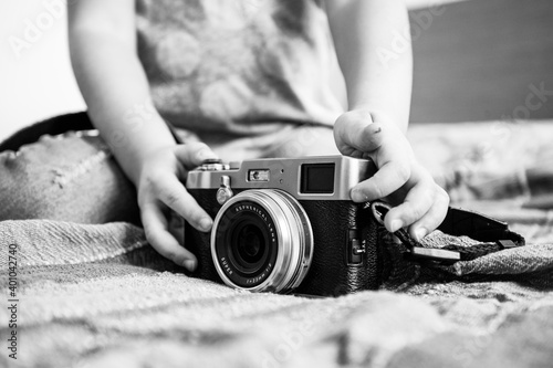 Close up of a mirrorless retro camera on the blanket - Little girl playing with camera - Talented little girl has fun with vintage camera at home - Leisure activity at home - Black and White