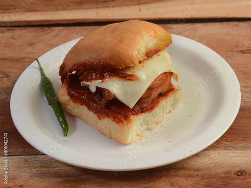 Cheese Vada Pav, Mumbai Famous vada paav is an indian burger. Potato patty is deep fried and stuffed inside a paav or bun like burger, served over a rustic wooden background, selective focus photo