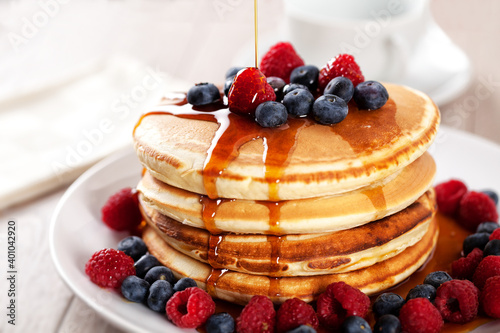 Pancakes with berries and maple syrup on a plate.