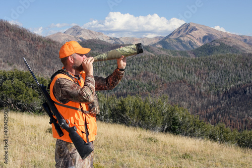 Tableau sur toile adult rifle hunter blowing elk calls through bugle tube in mountains