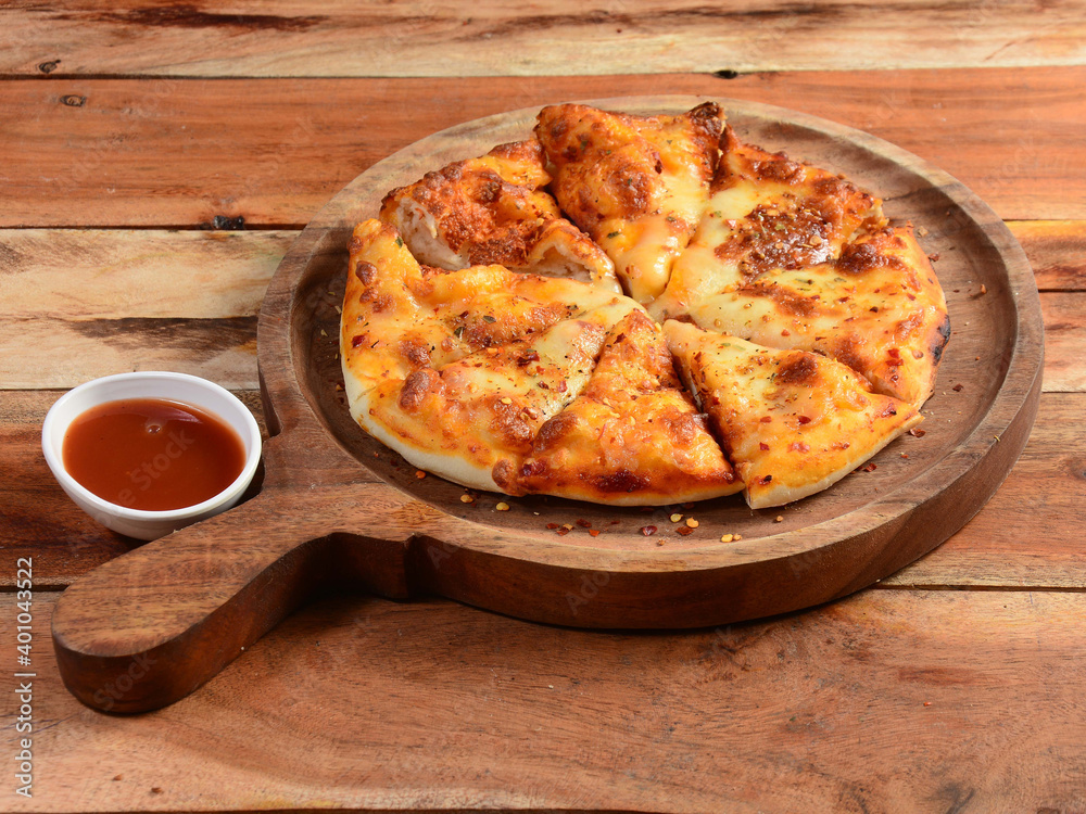 Veg Cheese Pizza with ketchup on wooden pizza board, isolated over a rustic wooden background, selective focus