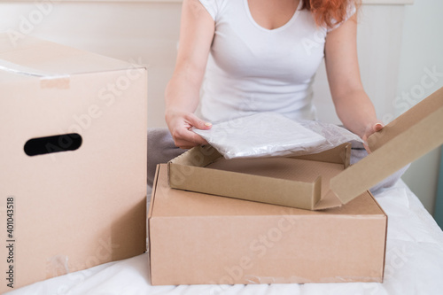Caucasian woman opens an order while sitting in bed. Online shopping concept with home delivery
