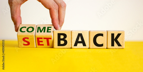 Setback or comeback symbol. Male hand flips wooden cubes and changes the word 'setback' to 'comeback'. Beautiful yellow and white background, copy space. Business and comeback concept.