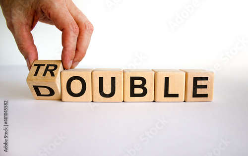 Double trouble symbol. Male hand flips a wooden cube with words 'Double trouble'. Beautiful white background, copy space. Business and double trouble concept.