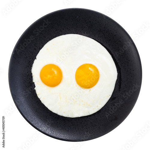 top view of two fried eggs on black plate isolated on white background