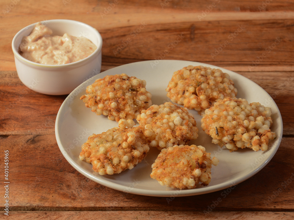 Sabudana vada or Sago fried cake served with chutney, popular fasting recipe from India. isolated over a rustic wooden background, selective focus Sabudana vada or Sago fried cake served with chutney, popular fasting recipe from India. isolated over a rustic wooden background, selective focus