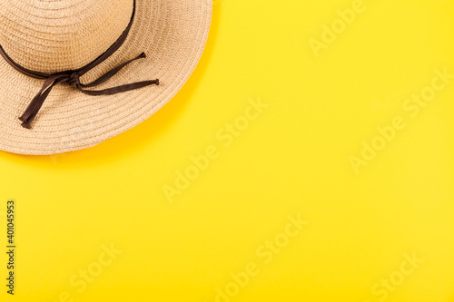 Top view on a retro straw hat on a yellow background. Summer concept. Minimalistic wallpaper for advertising a happy vacation on the sea or ocean or travel agency services with free place for text.