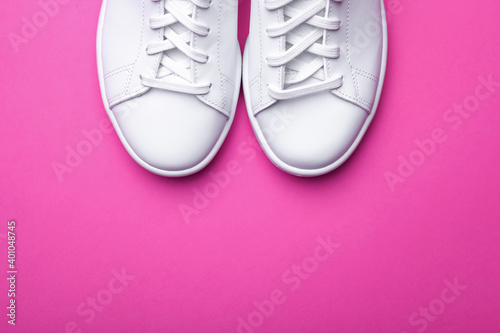Pair of stylish sport shoes on pink background. Top view of white sneakers on color background with space for text 
