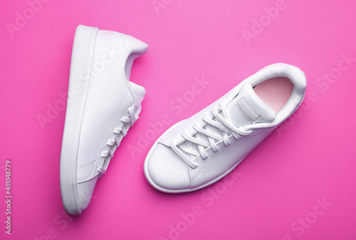 Pair of stylish sport shoes on pink background. Top view of white sneakers on color background 