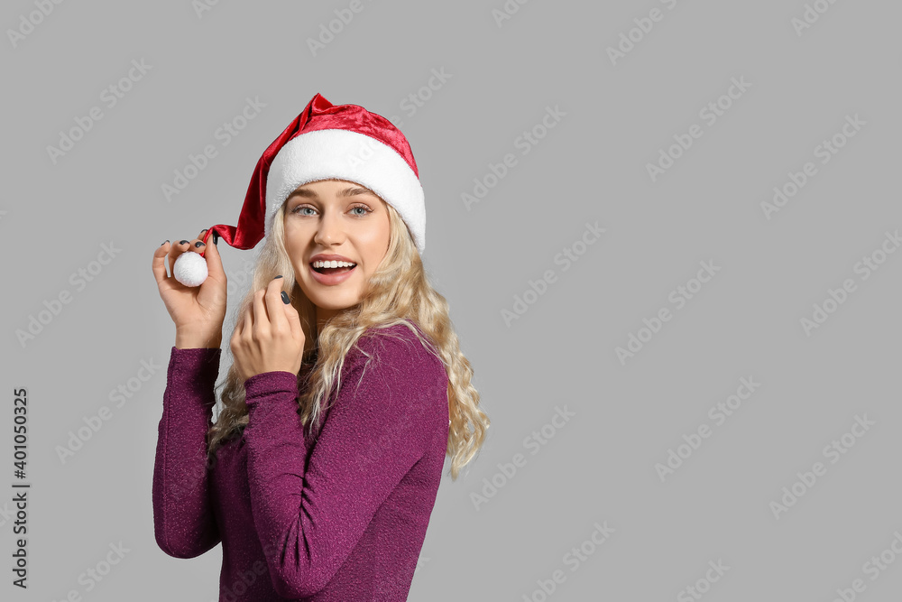 Beautiful young woman in Santa hat on light background Beautiful young woman in Santa hat on light background