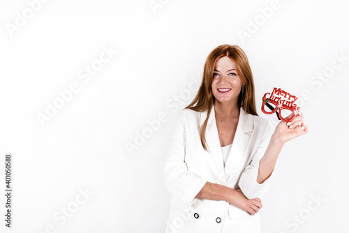 Happy beautiful woman holding funny eyeglasses with Merry Christmas superscription isolated on the studio white background photo