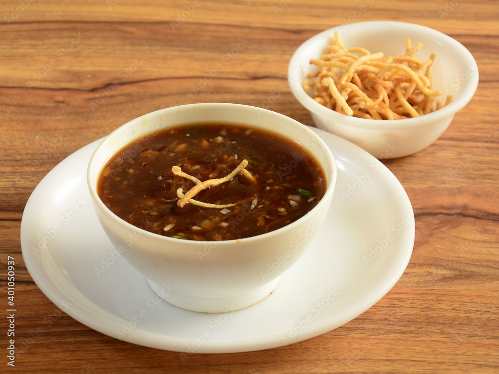 Manchow soup, indo chinese dish served over a rustic wooden background, selective focus Manchow soup, indo chinese dish served over a rustic wooden background, selective focus