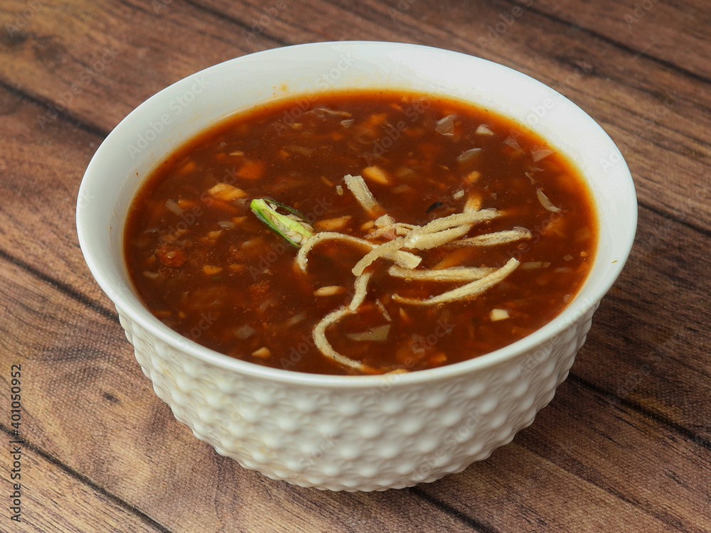 Manchow soup, indo chinese dish served over a rustic wooden background, selective focus Manchow soup, indo chinese dish served over a rustic wooden background, selective focus