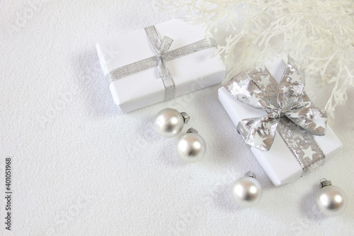 Christmas background with gifts, baubles and twigs in silver and white 