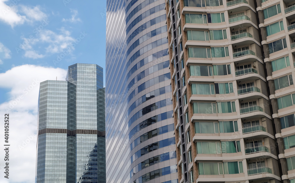 Bangkok, Thailand - July 10, 2019 : Angular geometric mirror cladding on a modern building with repeating structure and reflected sky and clouds. No focus, specifically.