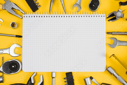 Tools top view on yellow background. Plier, open wrenches, screwdrivers and staple gun flat lay with copy space.