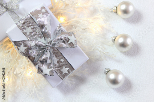 Bożonarodzeniowa srebrno-biała dekoracja z prezentami, bombkami i oszronionymi gałązkami 